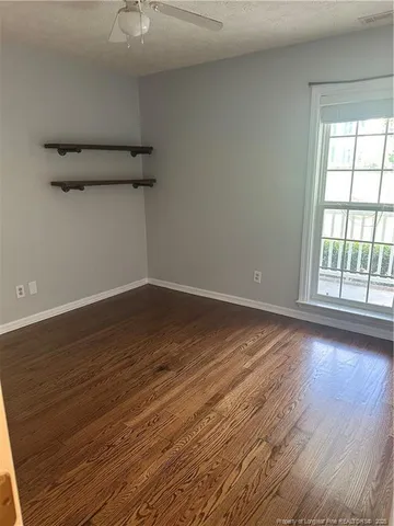 an empty room with wooden floor fireplace and windows