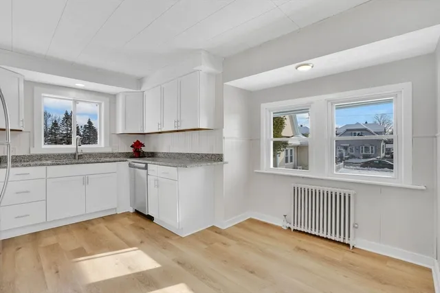 a kitchen with white cabinets and window