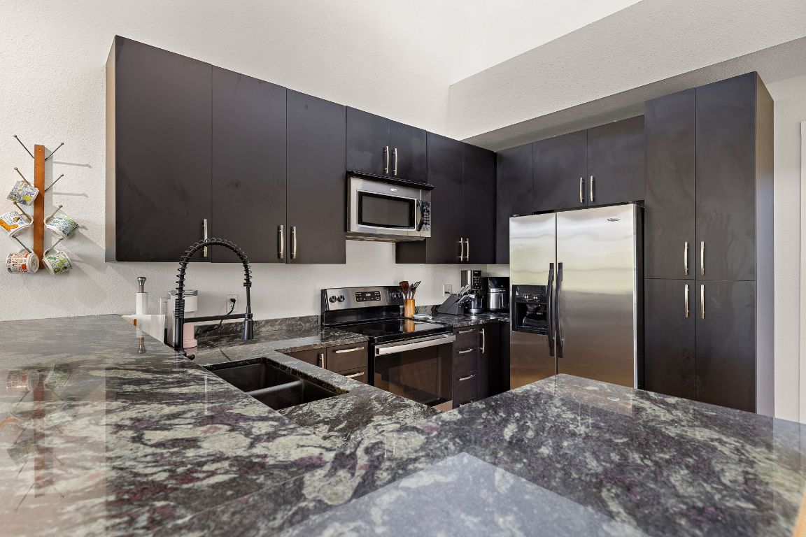 907 Duncan Lane, Unit 302 Austin, TX 78705 - Photo 10 of 24 a kitchen with stainless steel appliances granite countertop a refrigerator stove and oven