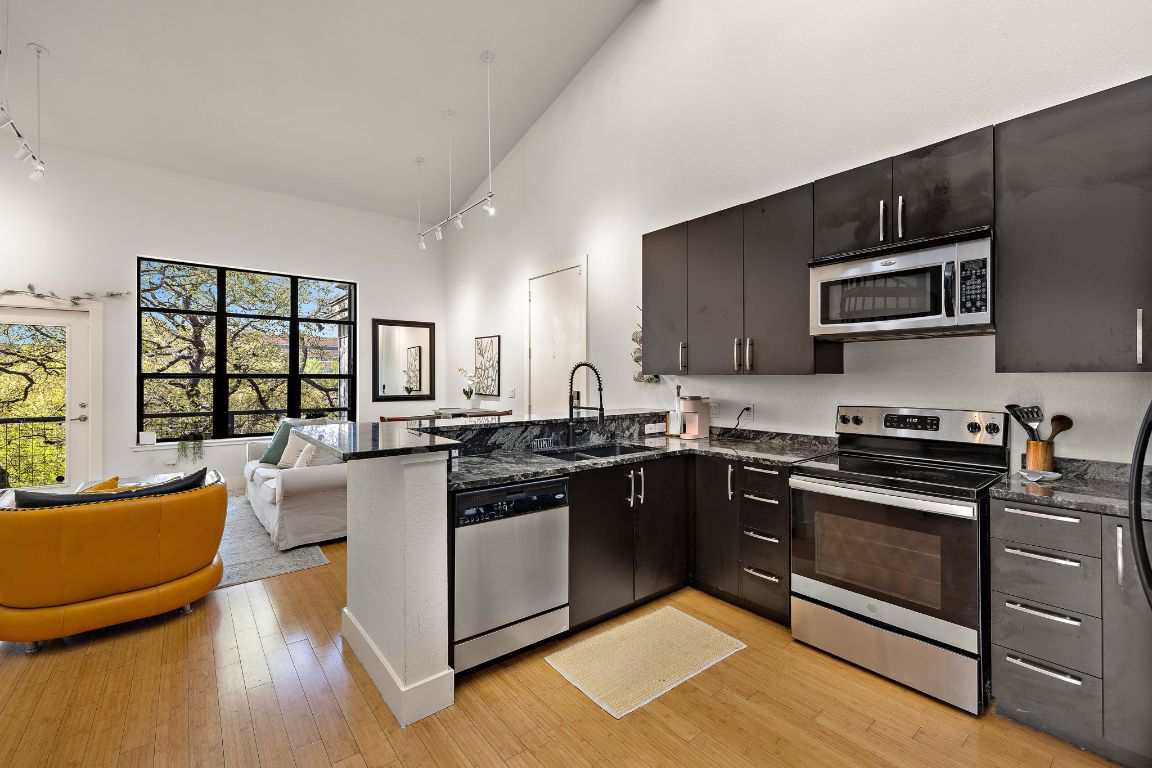 907 Duncan Lane, Unit 302 Austin, TX 78705 - Photo 12 of 24 a kitchen with stainless steel appliances granite countertop a stove top oven a sink dishwasher a dining table and chairs with wooden floor
