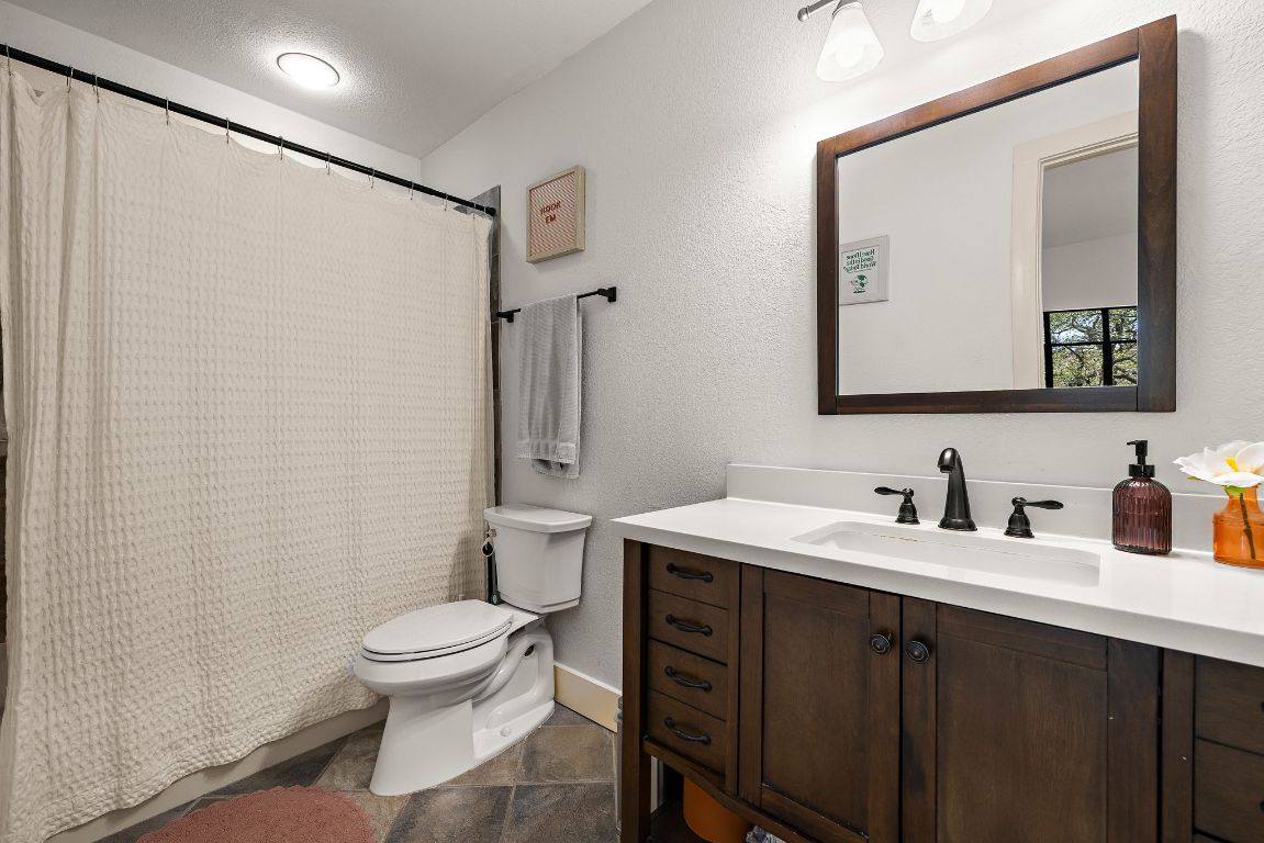 907 Duncan Lane, Unit 302 Austin, TX 78705 - Photo 18 of 24 a bathroom with a toilet sink vanity and mirror
