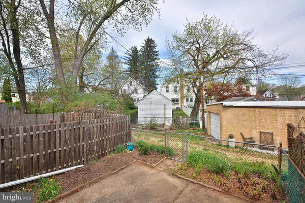 a view of a backyard with wooden fence and large trees