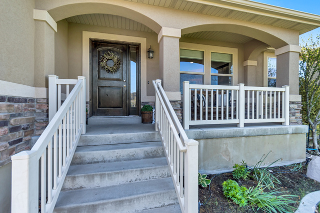 983 West 1550th Street South Springville, UT 84663 - Photo 3 of 43 Inviting front entry featuring a cute covered porch, white railings, a dark wood-finish entry door, and a built-in outdoor light fixture.