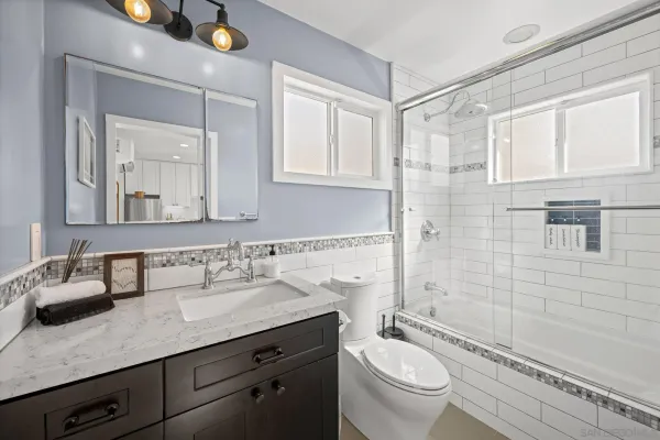 a bathroom with a granite countertop sink a toilet a mirror and shower