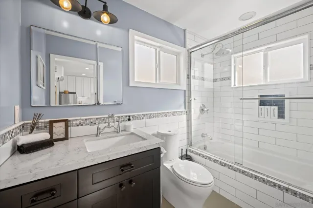 a bathroom with a granite countertop sink a toilet a mirror and shower
