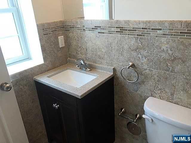 426 Jersey Street, Unit 1 GROUND Harrison, NJ 07029 - Photo 14 of 17 a bathroom with a sink mirror vanity and toilet