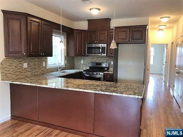 426 Jersey Street, Unit 1 GROUND Harrison, NJ 07029 - Photo 6 of 17 a kitchen with granite countertop wooden cabinets a refrigerator and a sink