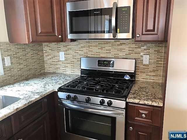 426 Jersey Street, Unit 1 GROUND Harrison, NJ 07029 - Photo 8 of 17 a kitchen with granite countertop a stove top oven cabinetry a sink and a microwave