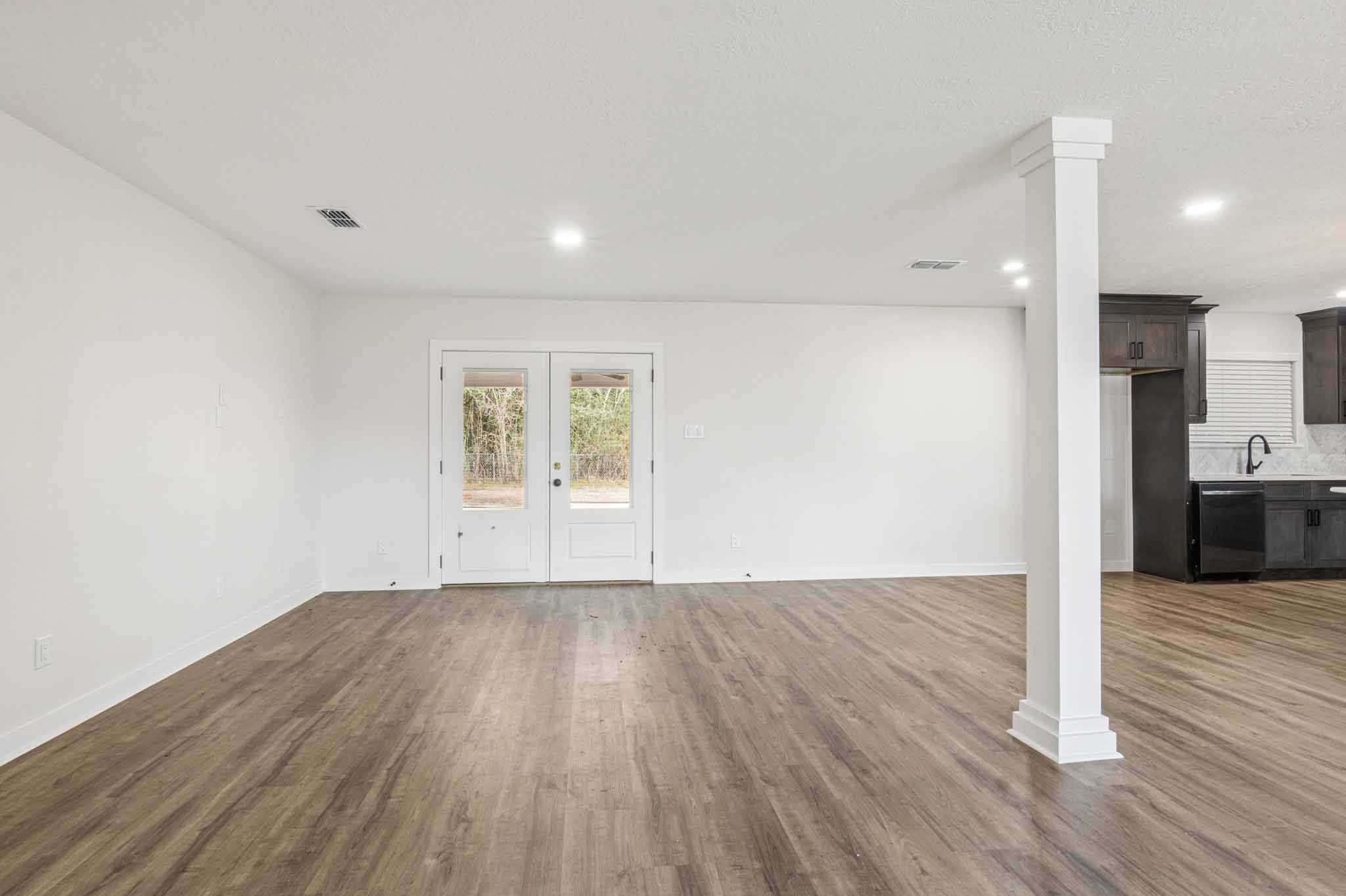 305 James Street Winnie, TX 77665 - Photo 7 of 25 a view of an empty room with wooden floor and a kitchen