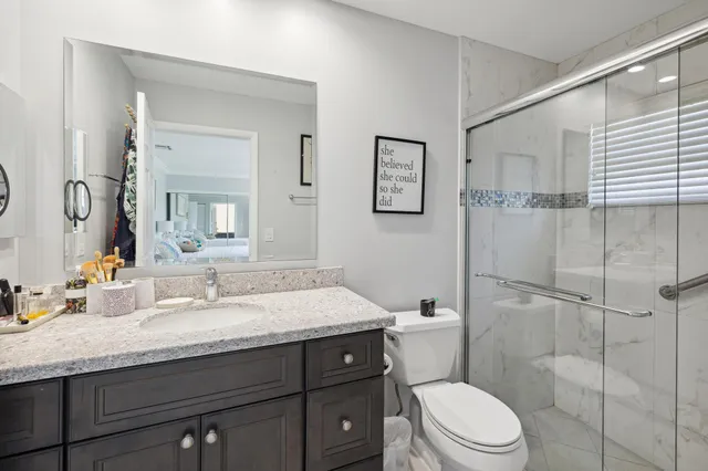 a bathroom with a granite countertop toilet sink and mirror