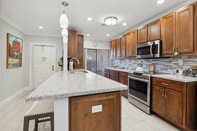 a kitchen with stainless steel appliances granite countertop a stove a sink dishwasher and microwave oven with wooden cabinets