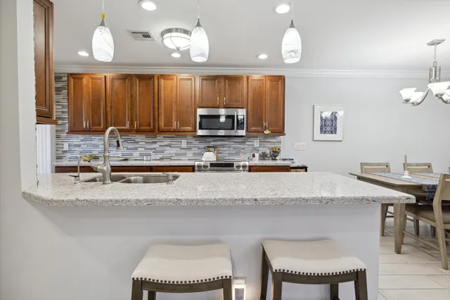 a kitchen with granite countertop a stove a sink a dining table and chairs