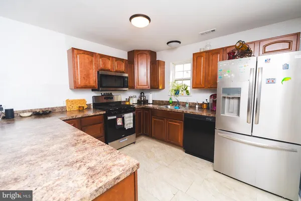 a kitchen with granite countertop a refrigerator stove top oven and sink