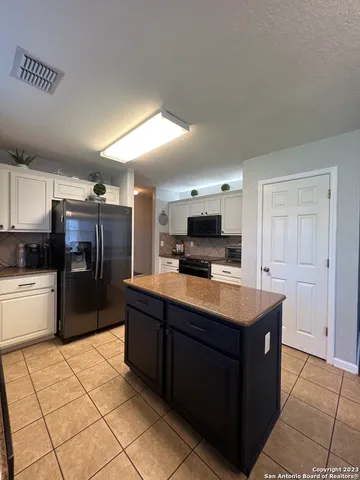 a kitchen with stainless steel appliances kitchen island granite countertop a refrigerator and a stove top oven
