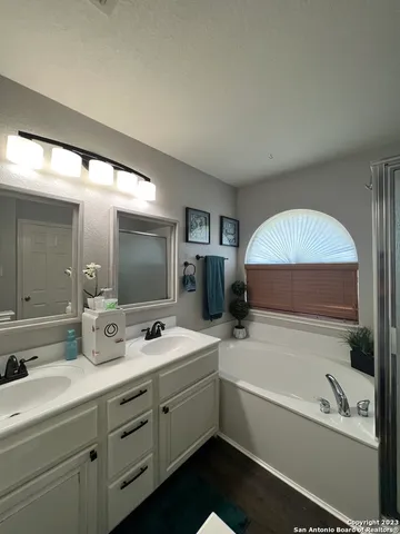 a bathroom with a double vanity sink mirror and bathtub