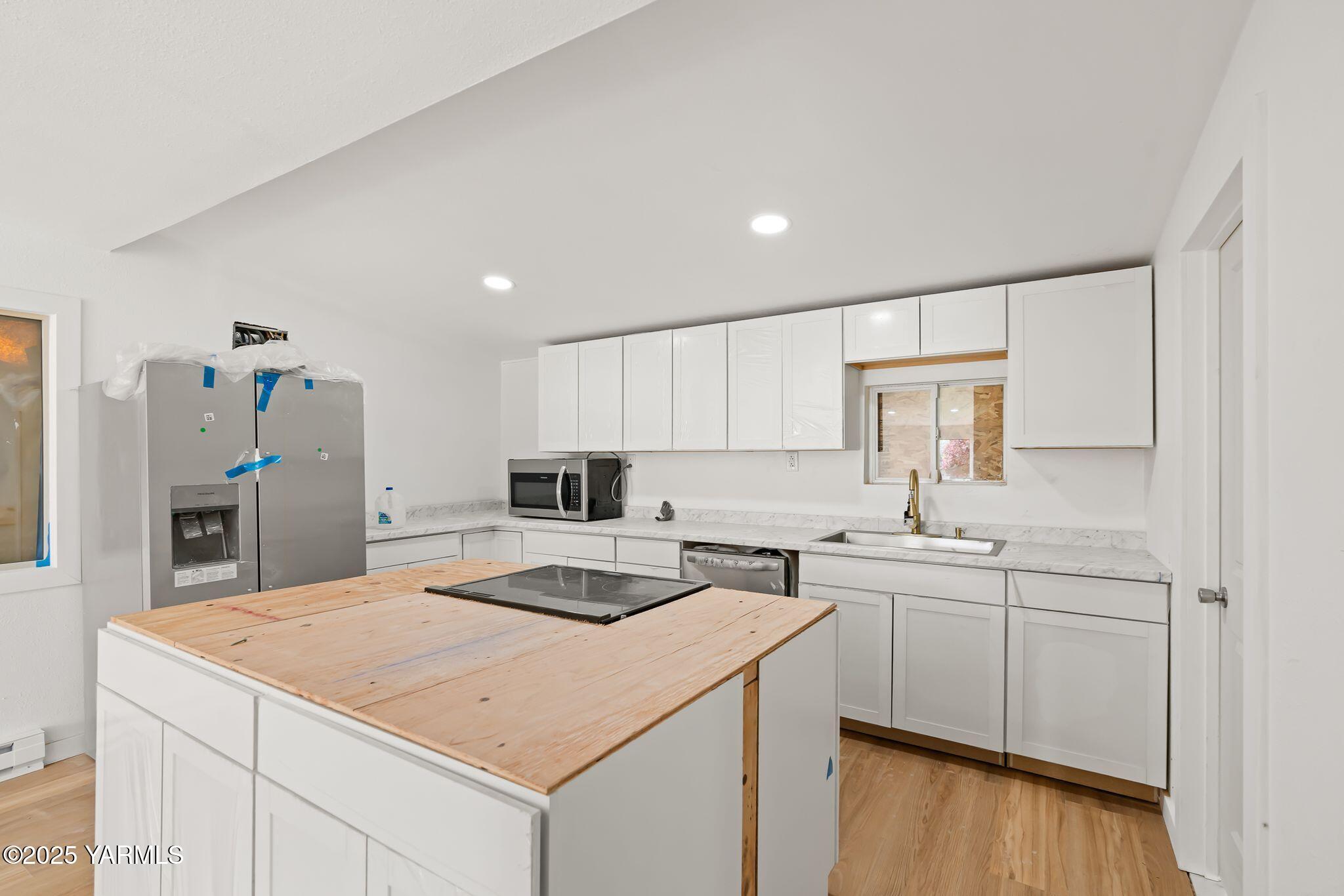 810 North 6th Avenue Yakima, WA 98902 - Photo 4 of 10 a kitchen with a sink a stove a refrigerator and white cabinets