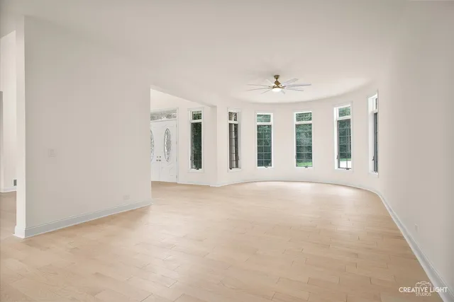 an empty room with windows and fan