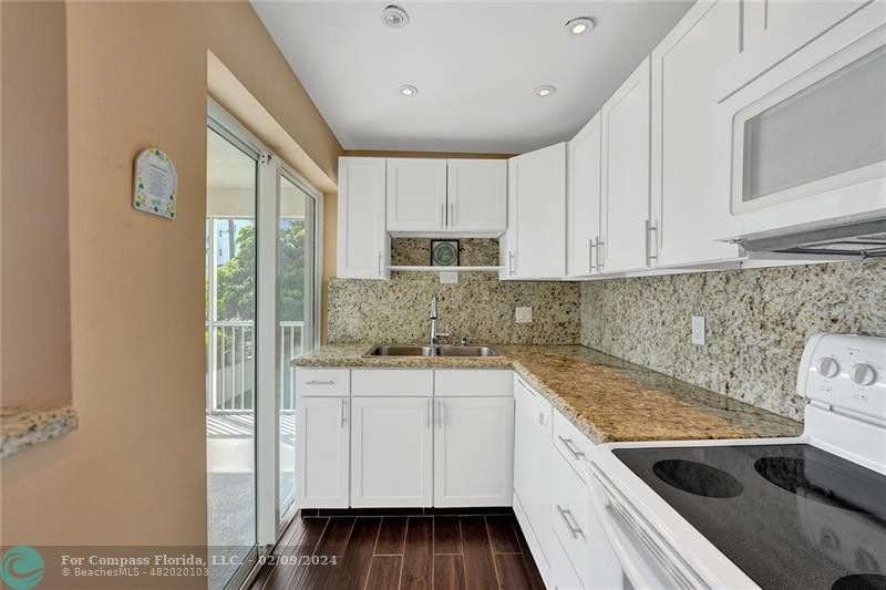 a kitchen with granite countertop white cabinets and white appliances
