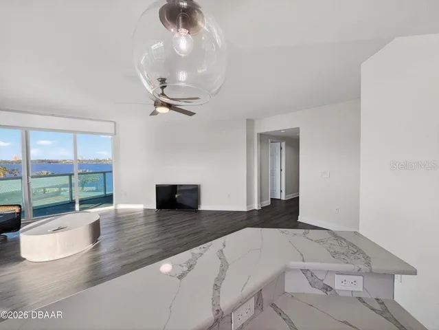 an empty room with wooden floor fan and windows