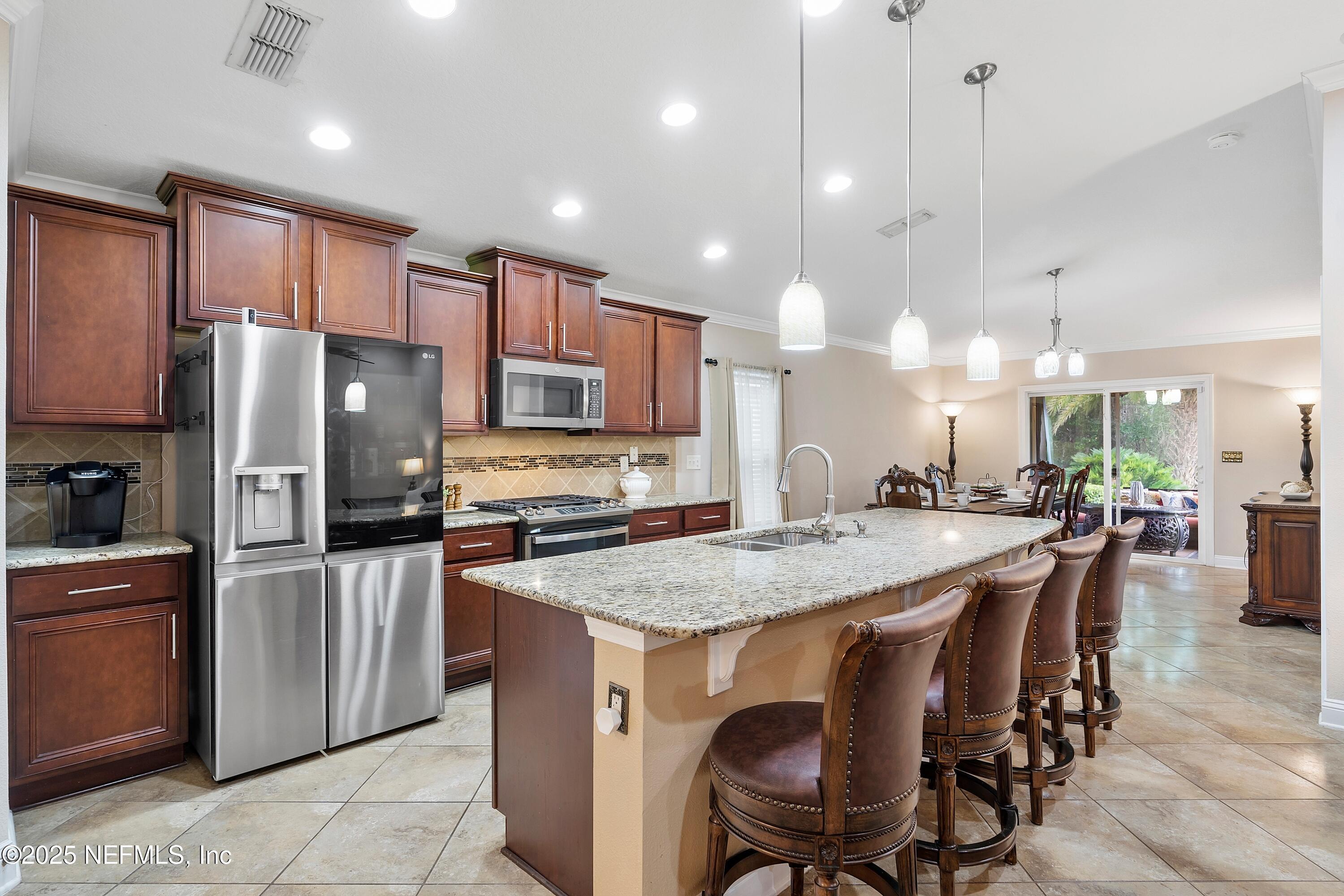 78 Wayfare Lane Jacksonville, FL 32081 - Photo 12 of 61 a kitchen with stainless steel appliances granite countertop a table chairs sink refrigerator and microwave
