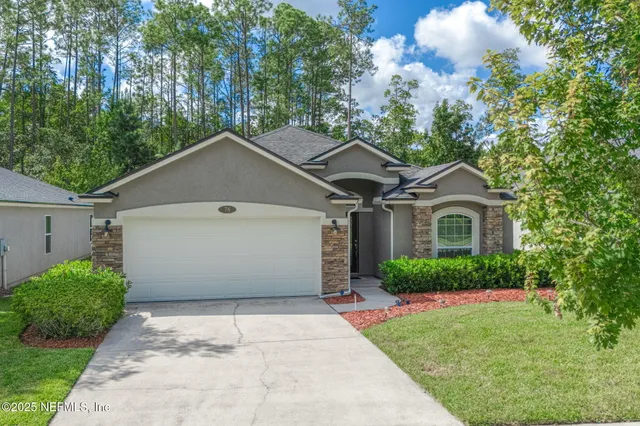 a white house with a small yard and big trees