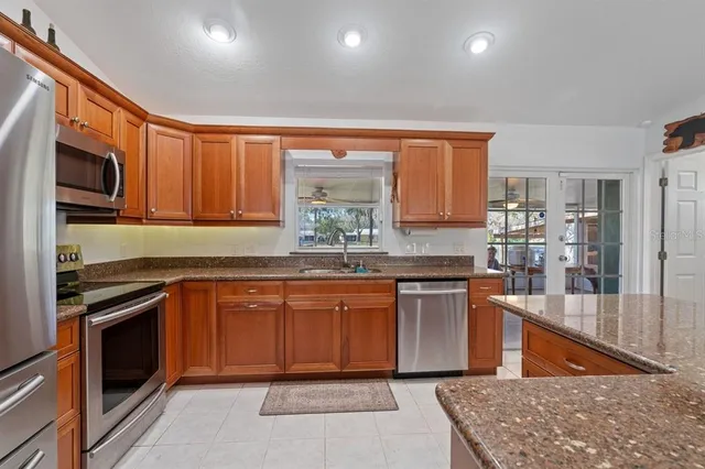 a kitchen with stainless steel appliances granite countertop wooden cabinets a stove a sink and a microwave