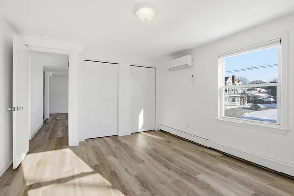 a view of an empty room with wooden floor and a window