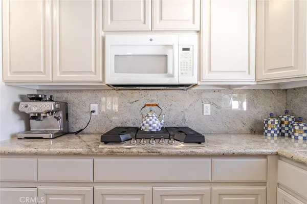 a kitchen with a granite countertop white cabinets and a stove