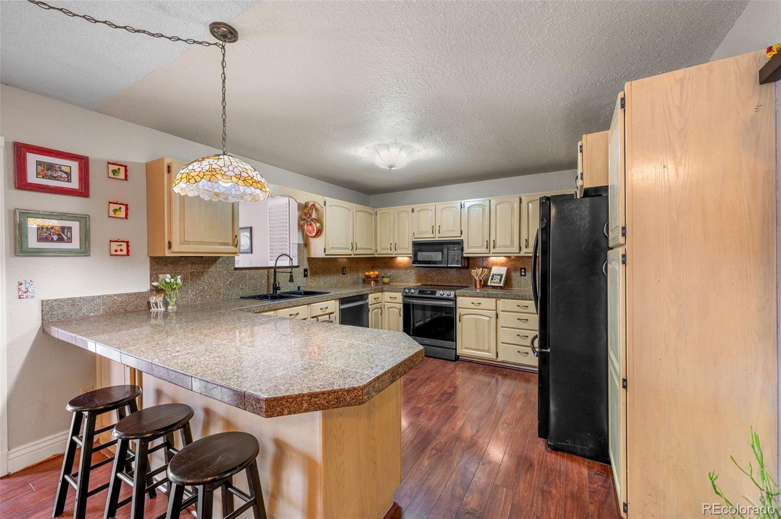 6263 Laodicea Road Longmont, CO 80503 - Photo 19 of 45 a kitchen with stainless steel appliances granite countertop a refrigerator a sink dishwasher a stove and a dining table with wooden floor