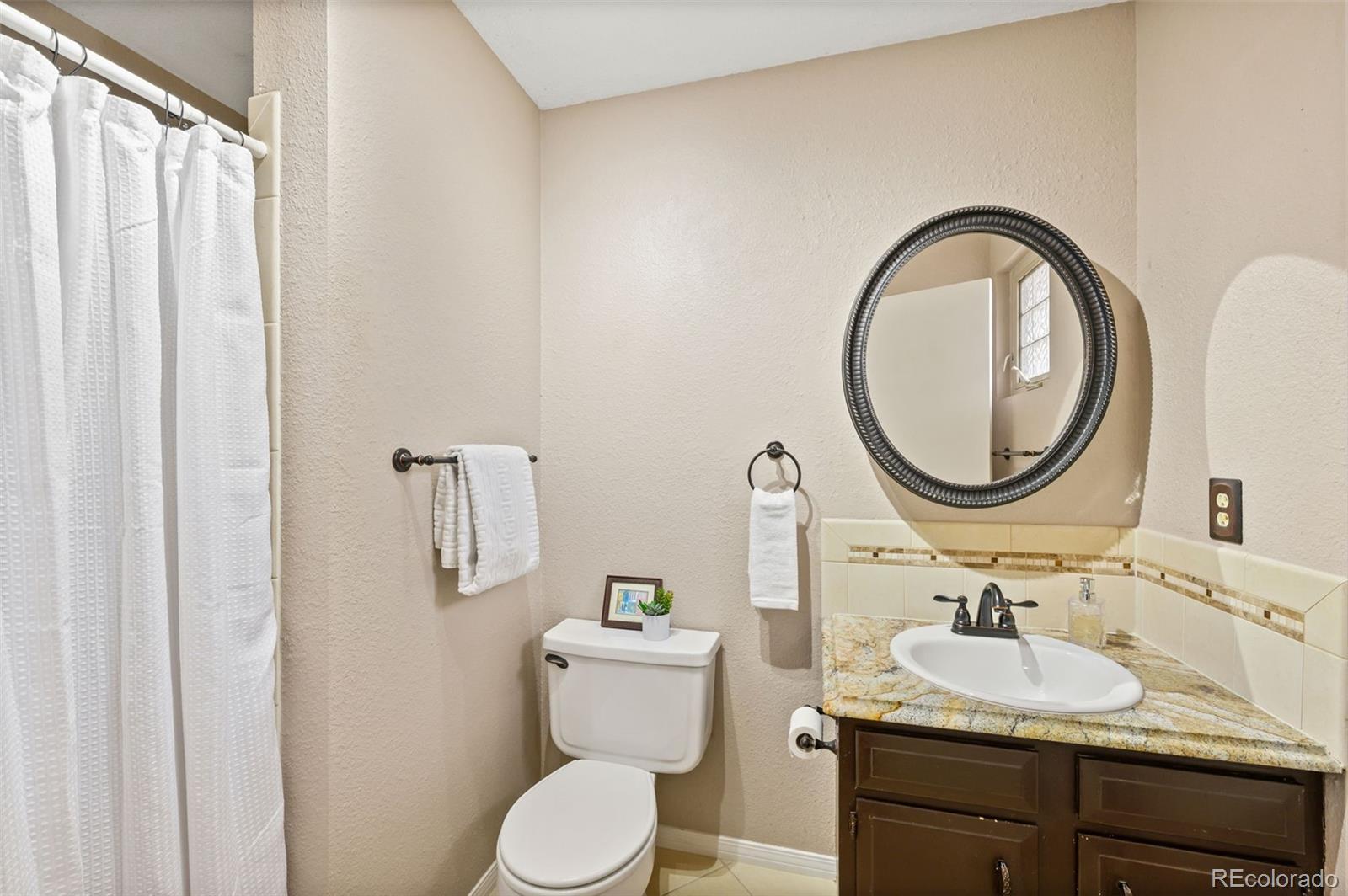 6263 Laodicea Road Longmont, CO 80503 - Photo 38 of 45 a bathroom with a granite countertop toilet a sink and a mirror