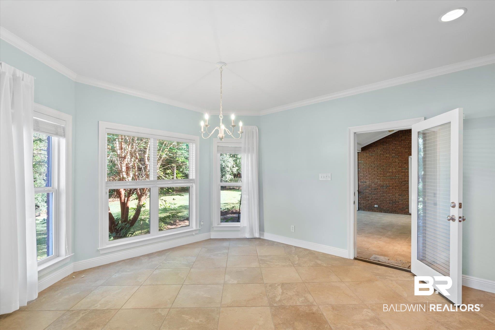 10730 Flagstone Drive Mobile, AL 36608 - Photo 9 of 20 Unfurnished dining area featuring an inviting chandelier, brick wall, crown molding, and a healthy amount of sunlight
