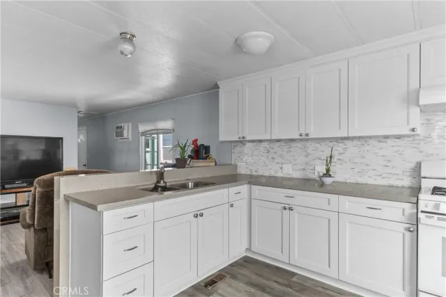 a kitchen with a sink dishwasher and white cabinets with wooden floor