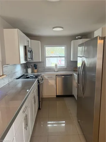 a kitchen with stainless steel appliances granite countertop a sink a stove a refrigerator a washer dryer and a cabinets