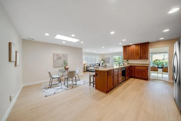 a open kitchen with stainless steel appliances kitchen island granite countertop a table chairs and a refrigerator