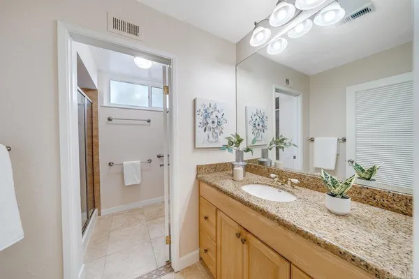 a bathroom with a granite countertop sink a light fixture and a mirror