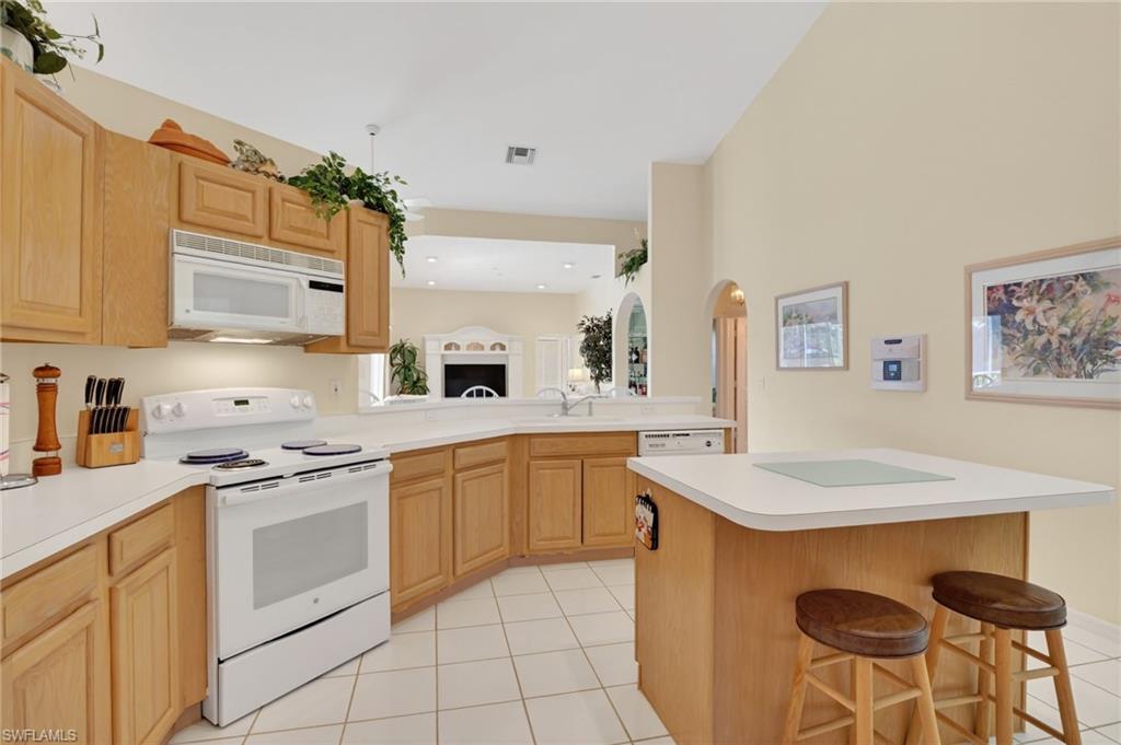 6687 Huntley Lane South Naples, FL 34104 - Photo 10 of 37 a kitchen with granite countertop white cabinets white appliances and chairs