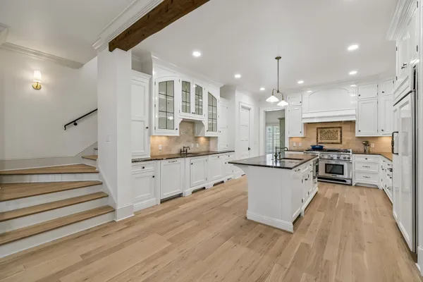a large kitchen with stainless steel appliances kitchen island a large counter top and a wooden floors