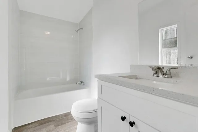 a bathroom with a granite countertop sink a toilet and shower