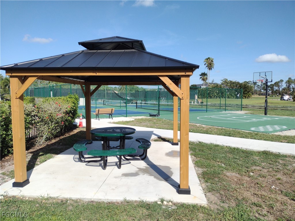4709 Fairloop Run Lehigh Acres, FL 33973 - Photo 22 of 25 a view of a patio with table and chairs under an umbrella