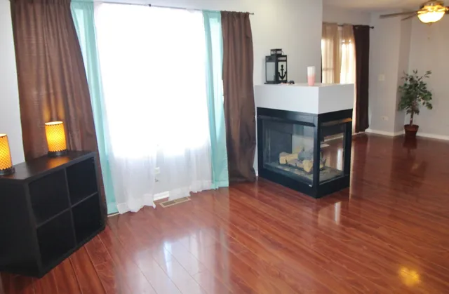 a view of an empty room with wooden floor and a fireplace