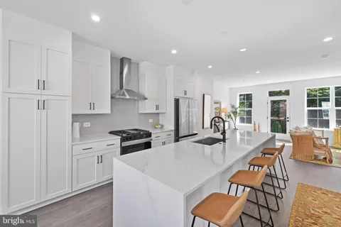 a kitchen with stainless steel appliances granite countertop a stove a refrigerator a kitchen island a dining table and chairs