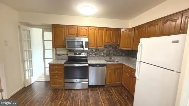 a kitchen with a refrigerator a stove and wooden floors