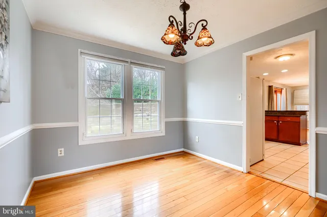 a view of an empty room with window and a chandelier fan
