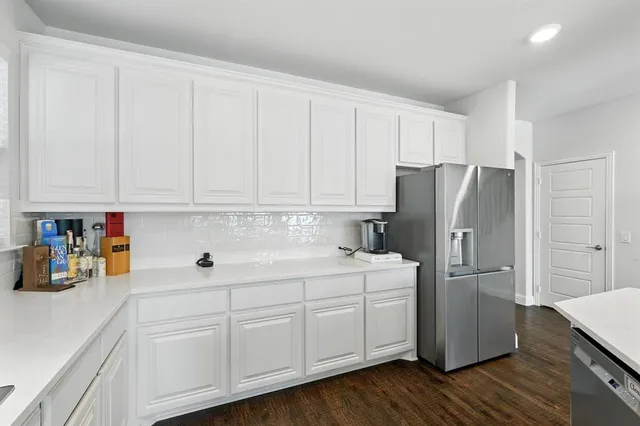 a kitchen with stainless steel appliances white cabinets and wooden floors