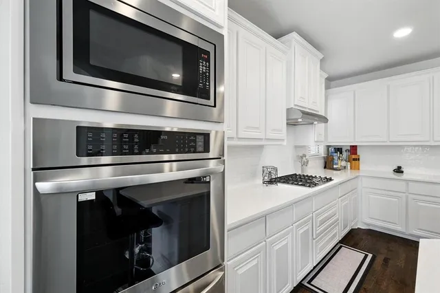 a kitchen with stainless steel appliances white cabinets and stove