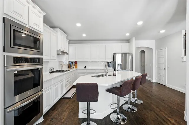 a kitchen with stainless steel appliances a stove a sink a microwave a refrigerator and cabinets