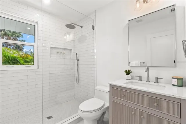 a bathroom with a granite countertop sink a toilet a mirror and shower