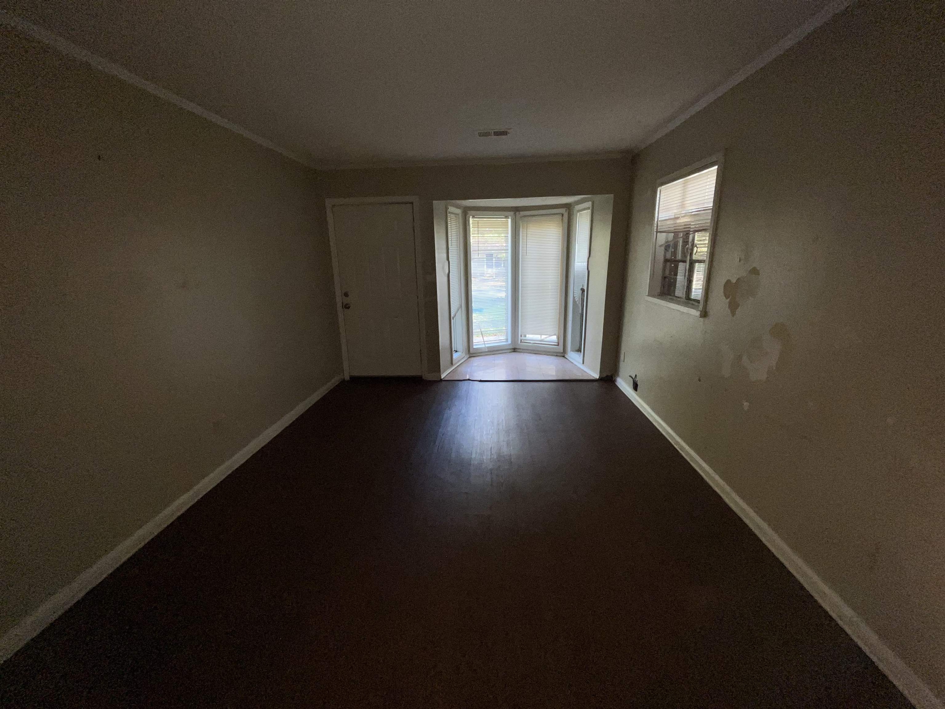 691 Delta Road Memphis, TN 38109 - Photo 4 of 25 a view of an empty room with wooden floor and a window