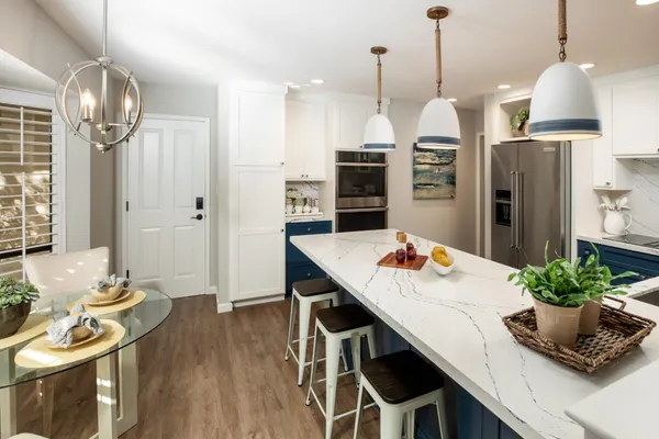 a kitchen with stainless steel appliances a dining table chairs and stove