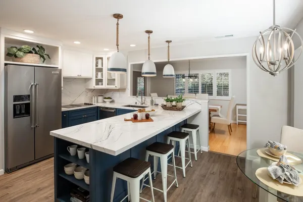 a kitchen with stainless steel appliances granite countertop a dining table chairs stove and refrigerator